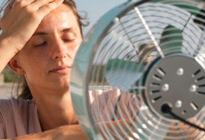 Foto einer Frau, die vor einem Ventilator sitzt