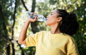 Foto einer jungen Frau, die aus einer Plastikflasche Wasser trinkt