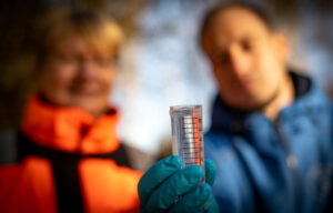 Foto von zwei Forschenden mit einer Wasserprobe