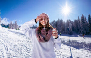 Foto einer Frau auf einer Skipiste, die sich das Gesicht eincremt