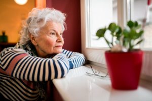 Aus dem Fenster blickende Seniorin