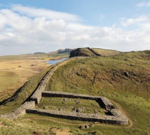 Milecastle_39,_Castle_Nick,_near_Steel_Rigg_on_Hadrian's_Wall,_with_Crag_Lough_in_the_distance,_Northumberland,_England._Hadrian's_Wall_was_built_73_miles_across_Britannia,_now_England,_122-128_AD,_under_the_reign_of_Emperor_Hadrian,_ruled_117-138,_to_mar