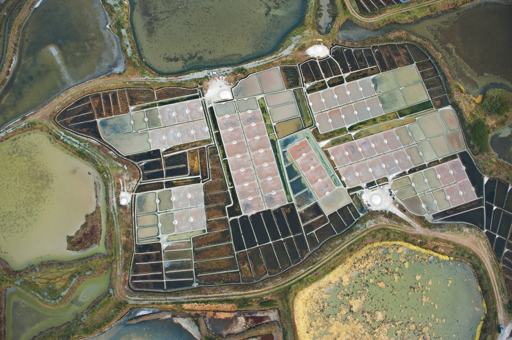 In die etwa 300 Salzgärten im französischen Guérande lassen die Bauern bei Flut Meerwasser einströmen. Das Wasser durchläuft lange Kanäle und mehrere Becken, damit es sich immer mehr konzentriert und schließlich in flachen Verdunstungspfannen kristallisiert. (Foto: © Mikel Landa / Landa-Ochandiano arquitectos)