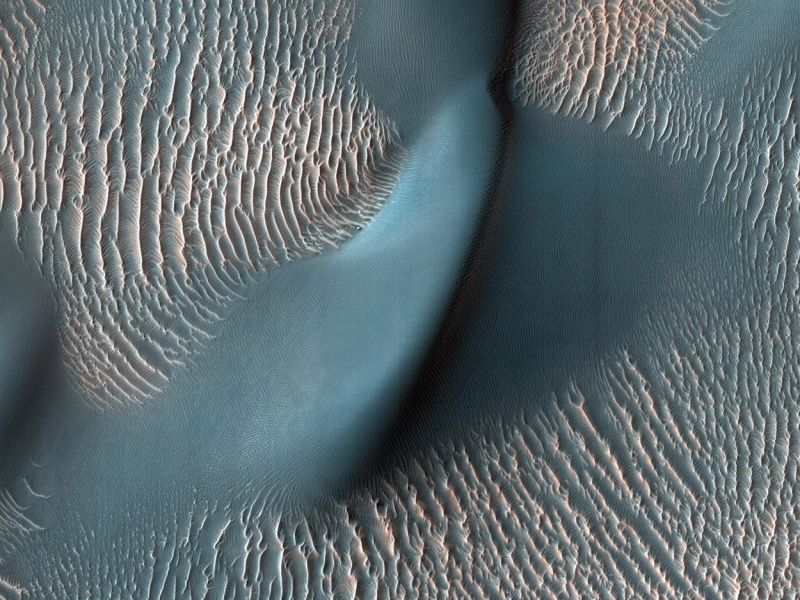 Dieses Foto zeigt eine große Marsdüne umgeben von vielen Sandrippen. Sie demonstrieren, wie der Wind die Oberfläche des Planeten formt. Die blaue Farbe wurde gewählt, um die Dünnen und Wellen der Oberfläche zu verdeutlichen. (Bild ©  NASA/JPL-Caltech/University of Arizona)