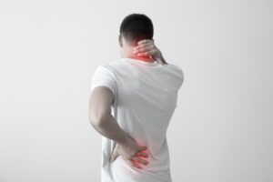 Young man suffering from back pain on light background