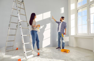 Paar bei Malerarbeiten in einem weißgetünchten Zimmer